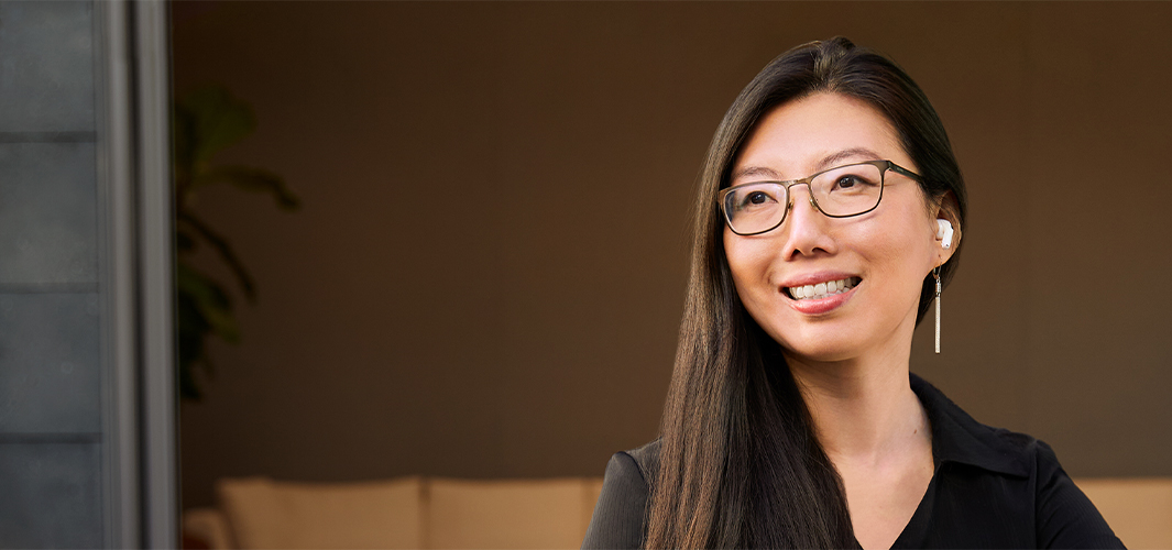 Jessica sitting outdoors with an office area in the background, smiling and looking off to her right.