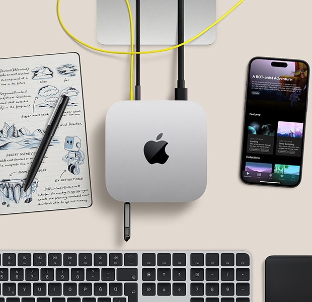 Bağlantı noktalarına bir flash bellek ile kabloların bağlı olduğu gümüş rengi Mac mini ile kablosuz klavye, trackpad, iPhone ve bir not defterinin bulunduğu masa düzeninin üstten görünümü