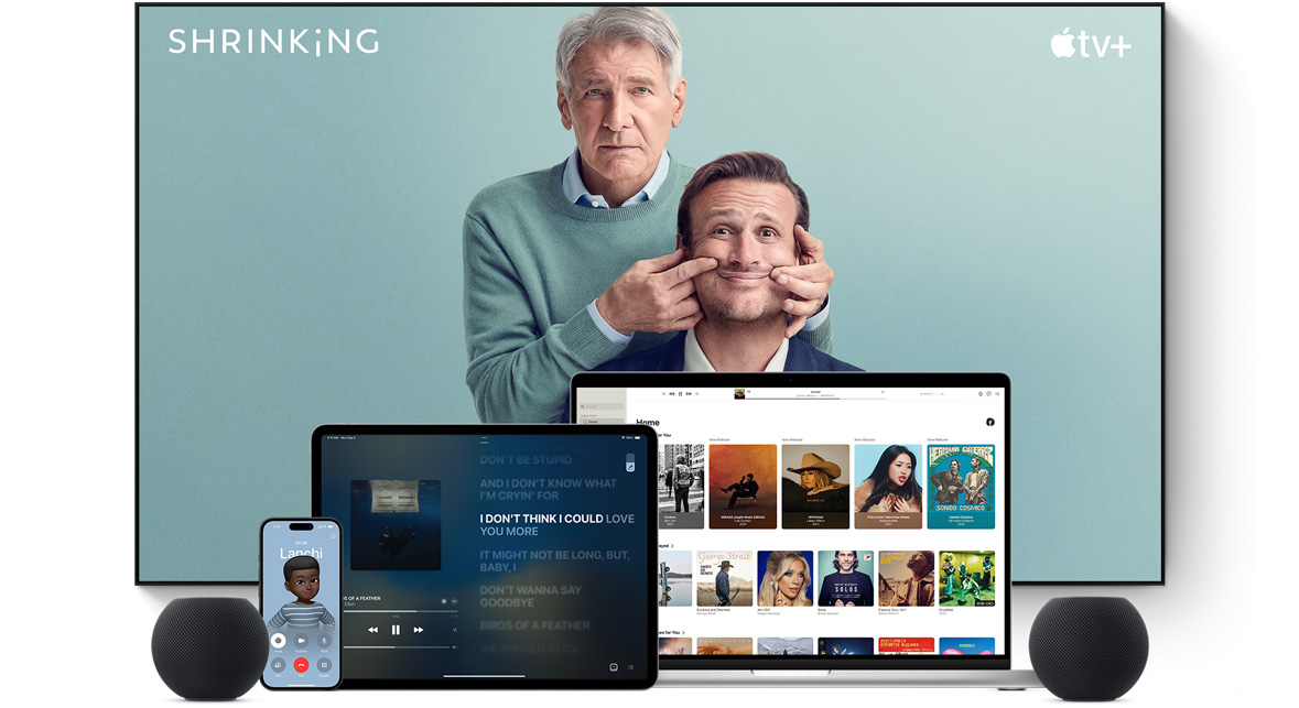 Large flat screen television showing two male characters from the Apple TV+ series shrinking. A MacBook Pro, an iPad, an iPhone, and a Midnight HomePod mini are arranged in front.