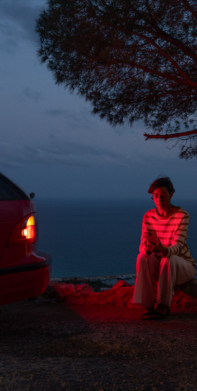 Photo d’une femme assise près d’une voiture en panne.