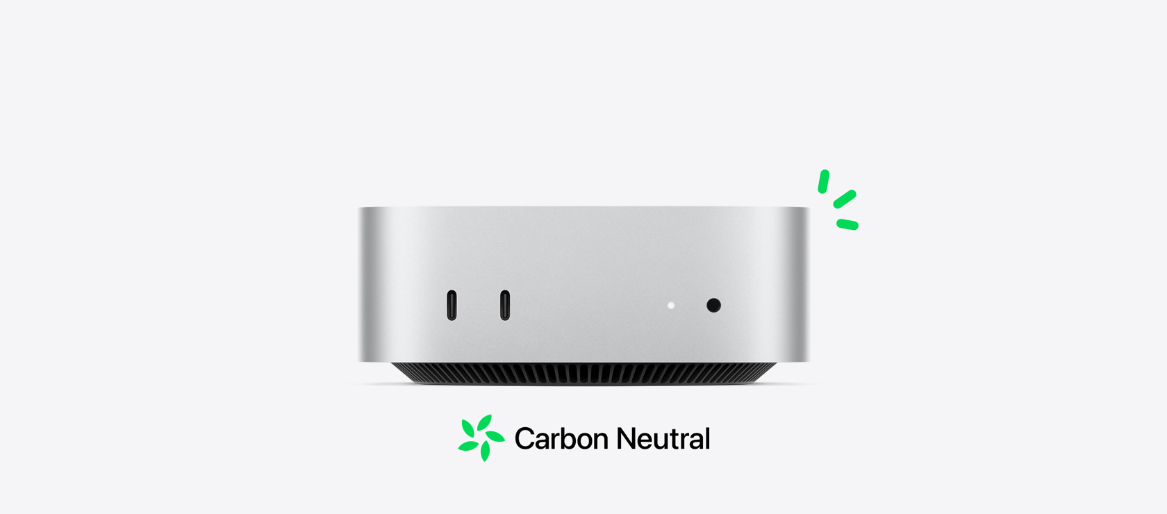 Pohľad spredu na strieborný Mac mini, na ktorom vidieť predné porty, pričom je jeho uhlíková neutralita ilustrovaná malými zelenými akcentmi.